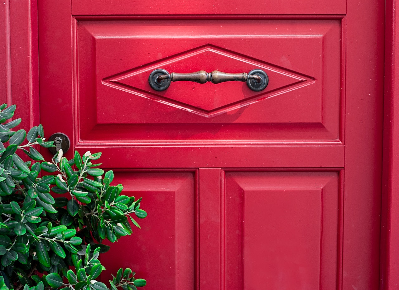 Red door with security lock hidden behind trees