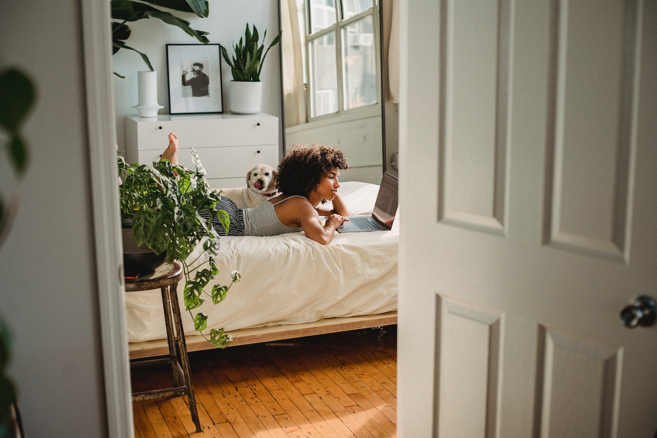 Woman with her pet dog browsing Teeho.com, choosing a stylish and secure fingerprint door lock for her bedroom.